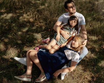 Portrait of father with two daughters lying on field