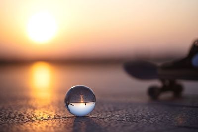 Close-up of crystal ball on beach against sky during sunset