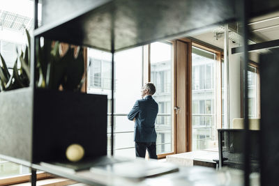 Businessman looking through glass window in office