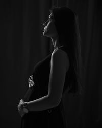 Side view of pregnant woman looking away while standing in darkroom