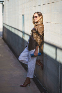 Portrait of young woman standing against wall