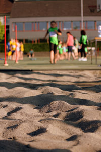 Close-up of sand with people playing in background