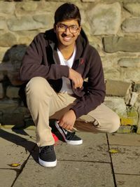 Portrait of smiling young man crouching outdoors