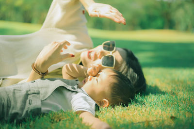 Rear view of woman lying on grass in field