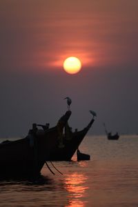 Silhouette boat in sea against sky during sunset