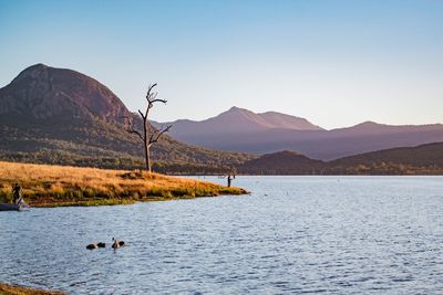 Scenic view of lake by mountains against clear sky