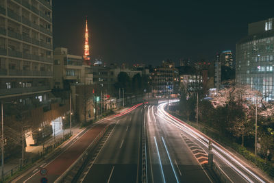 Light trails on road amidst buildings in city at night