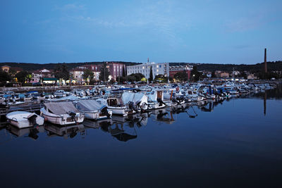 Sailboats moored in harbor against buildings in city