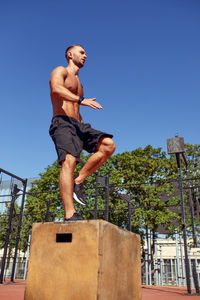 Low angle view of man jumping against sky