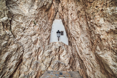 Low angle view of cross on rock amidst buildings