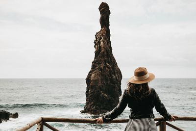 Rear view of woman with arms outstretched against sea