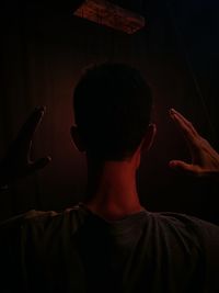 Rear view of man gesturing in darkroom