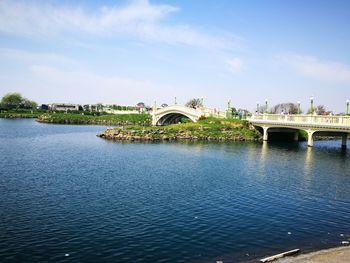 Arch bridge over river against cloudy sky