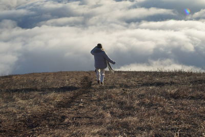Rear view of man on field against sky