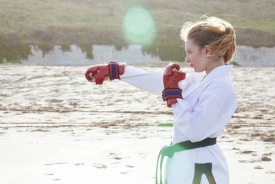 Cute girl practicing karate on beach