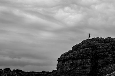 Low angle view of person on rock against sky