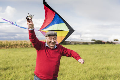 Happy senior man flying kite in rural landscape