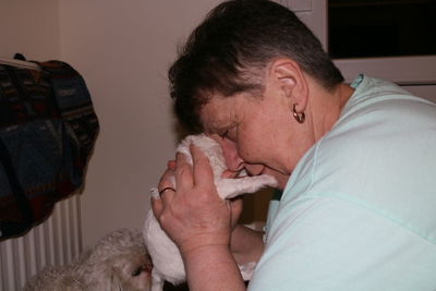 Side view of woman holding bichon frise puppy