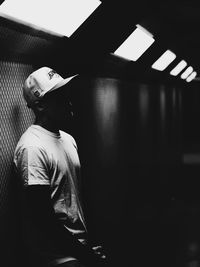 Man wearing hat standing against wall