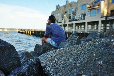 Rear view of man standing by sea against sky