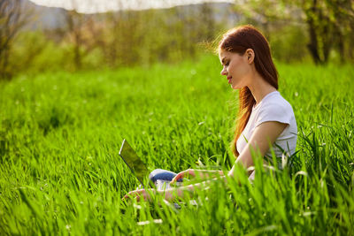 Portrait of young woman sitting on grassy field