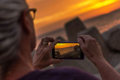 Close-up of woman using mobile phone during sunset 