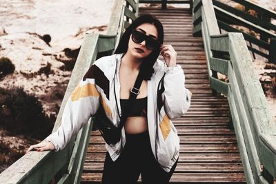 Portrait of young woman wearing sunglasses sitting on staircase