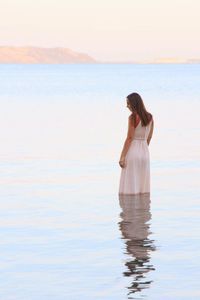 Woman standing in sea against sky