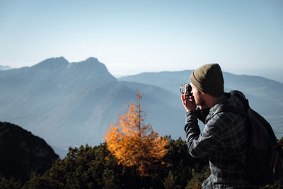 Man photographing on mountain against sky