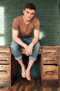 Handsome young man in t-shirt and jeans sits on the table