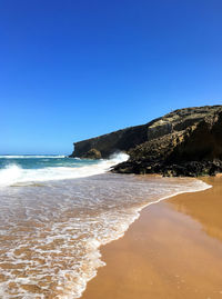 Scenic view of beach against blue sky