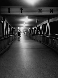 Rear view of woman walking on illuminated bridge