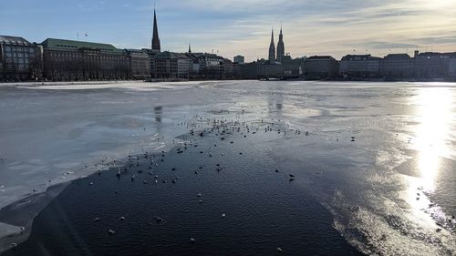 River by buildings against sky during sunset in city