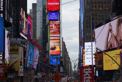 Advertisements on modern buildings in city against sky