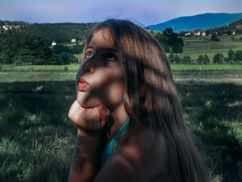 Portrait of young woman looking away on field