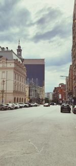 Buildings in city against cloudy sky