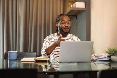 Portrait of young man using laptop at home