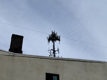 Low angle view of telephone pole against building