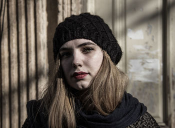 Close-up portrait of young woman standing against wall