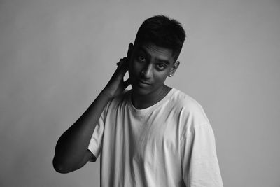 Portrait of young man standing against backdrop