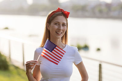 Portrait of young woman standing against railing