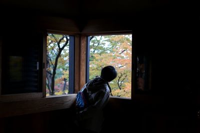 Rear view of man standing against window