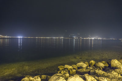 Close-up of illuminated sea against sky at night