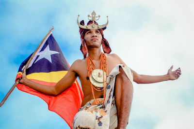 Low angle view of man in costume holding flag against sky
