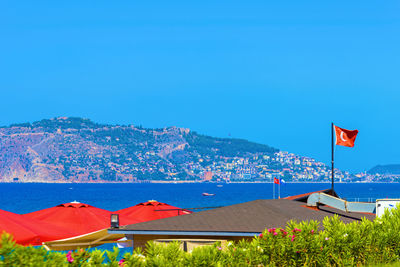 Turkish flag by sea against clear blue sky