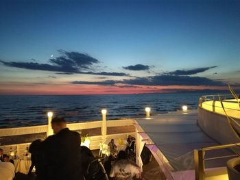 People looking at sea at sunset