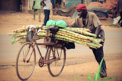 Rear view of man standing by bicycle