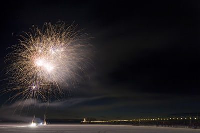 Firework exploding over landscape against sky at night