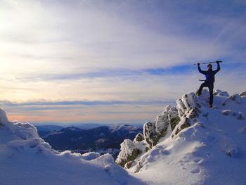 Man holding ski poles while standing on snowcapped mountain at guadarrama