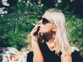 Close-up of beautiful woman smoking on field